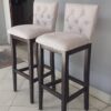Banqueta de madera con respaldo y asiento tapizados.