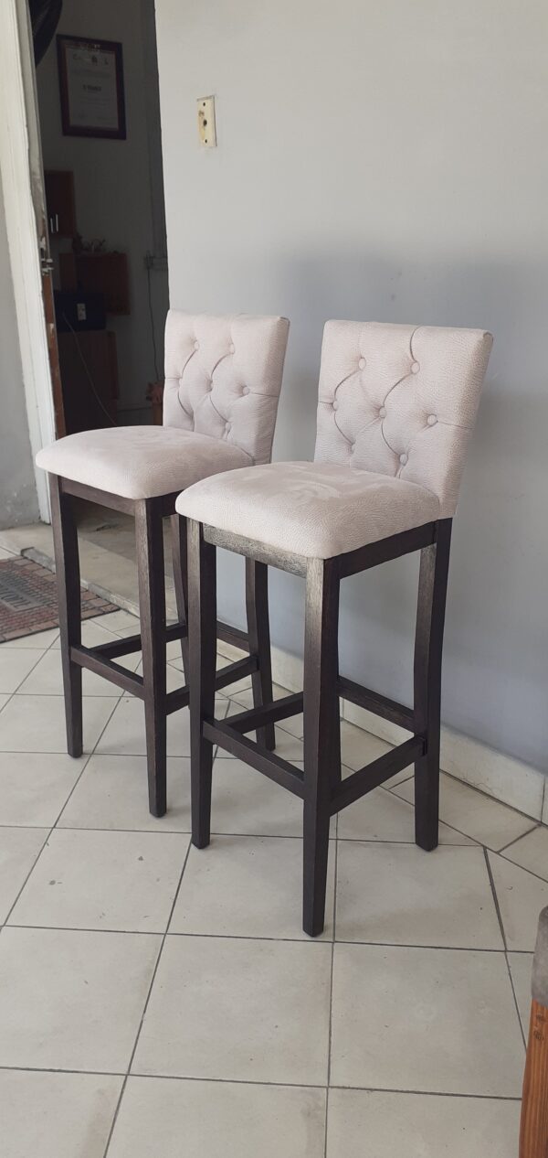 Banqueta de madera con respaldo y asiento tapizados.