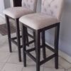 Banqueta de madera con respaldo y asiento tapizados.
