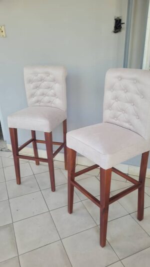 Banqueta de madera con respaldo y asiento tapizados.